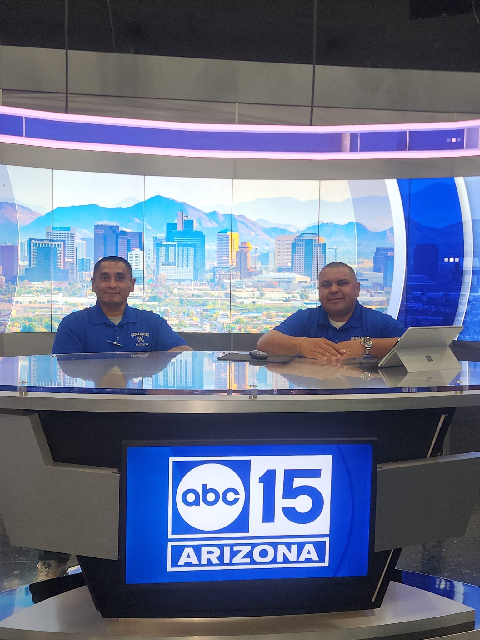 Two Garcia Movers team members in company blue at the ABC15 Arizona anchor desk