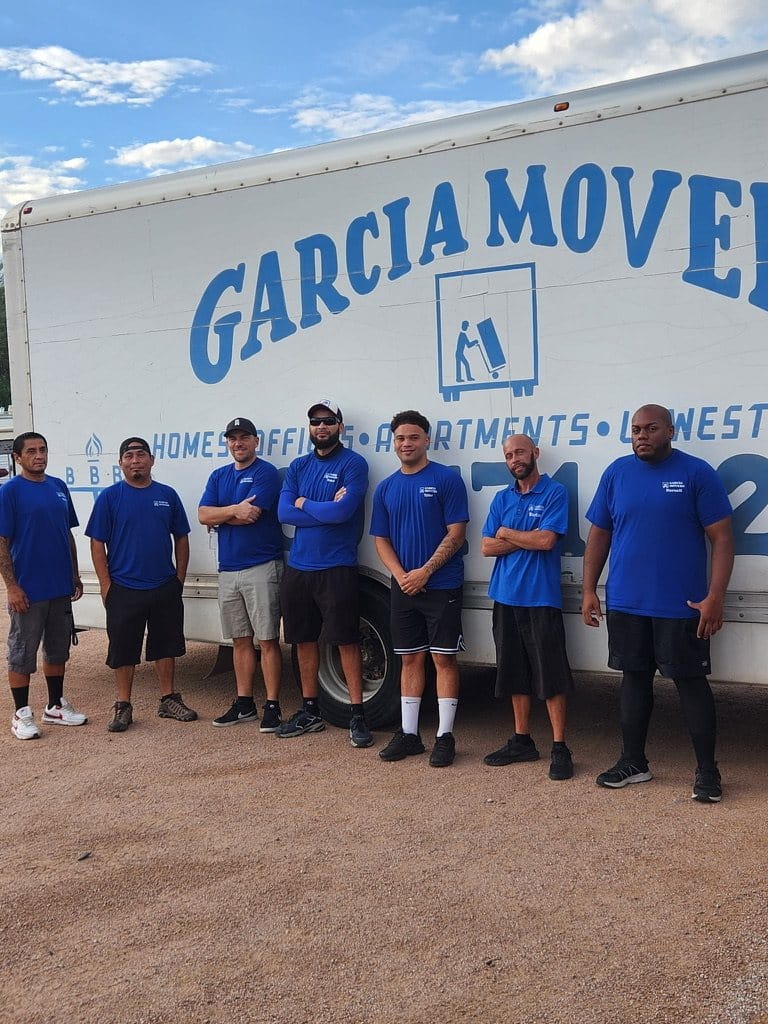 The Garcia Movers crew in company blue shirts in front of a branded moving truck