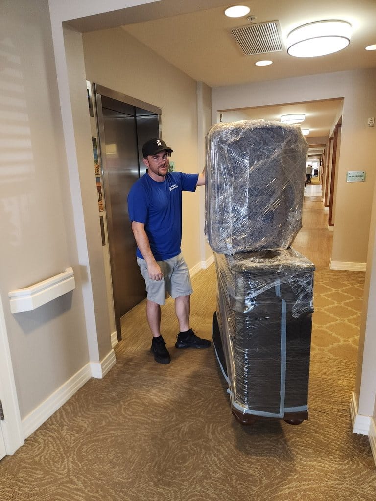 A Garcia mover bringing wrapped furniture through a senior living community