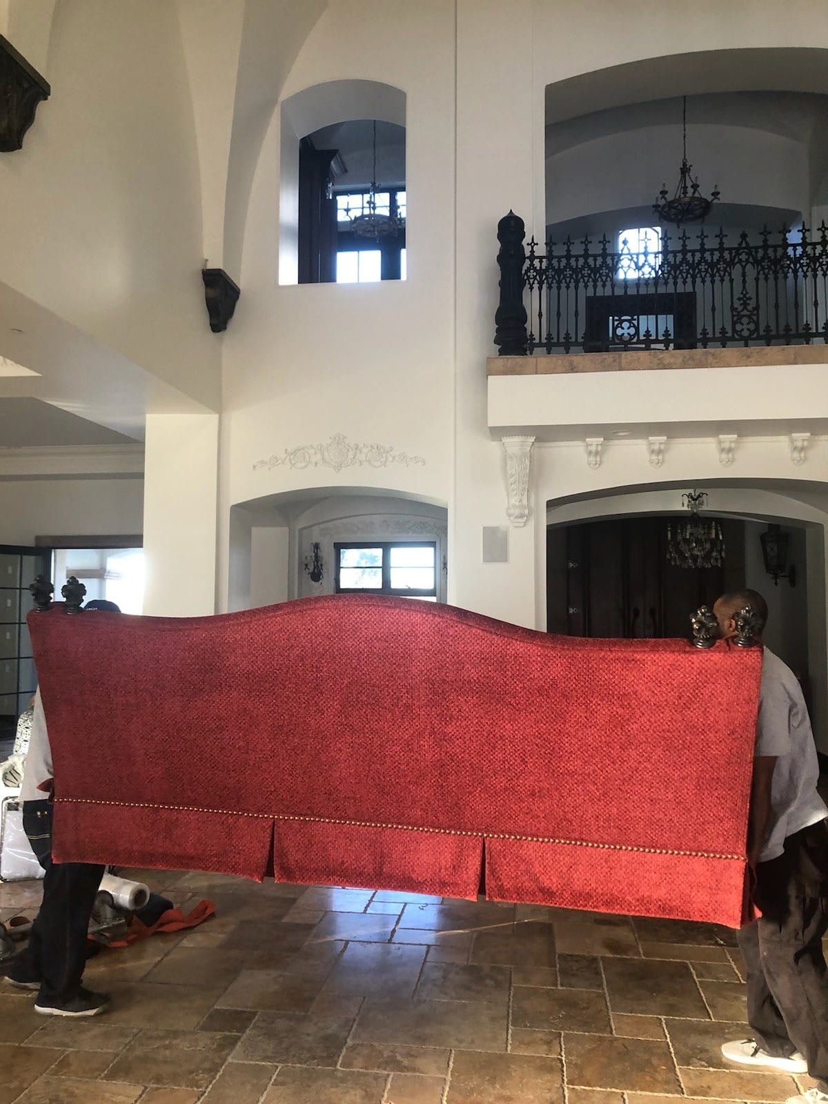 The crew carrying an antique sofa through a two-story foyer