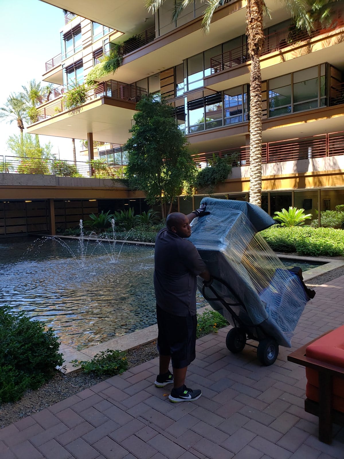 A Garcia mover wheeling a wrapped piece past the fountain at an upscale condo community