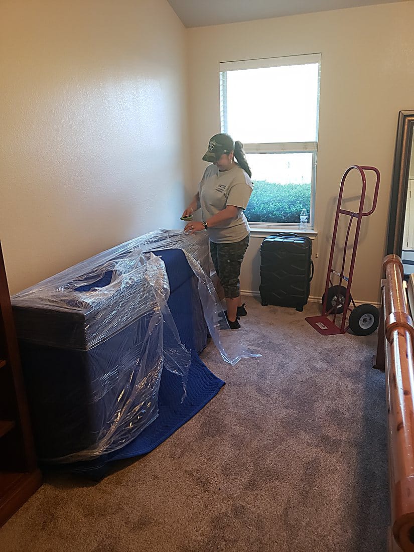 A Garcia mover padding and wrapping a bed