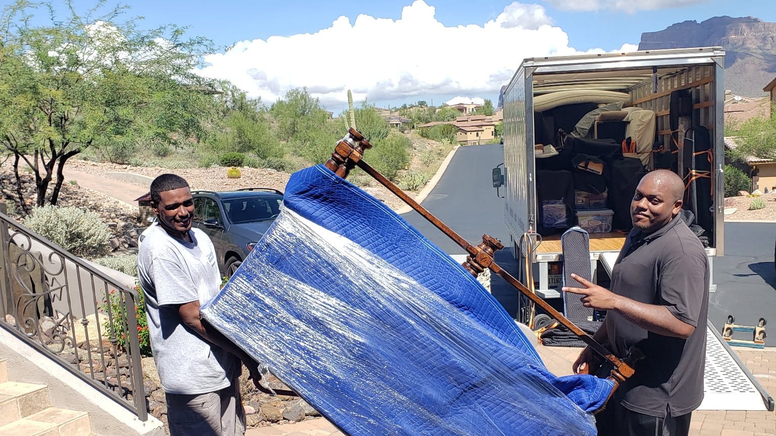 Two Garcia movers loading a blanket-wrapped piece into the open truck