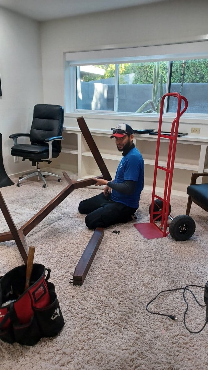 A Garcia mover reassembling furniture with tools laid out on protected carpet