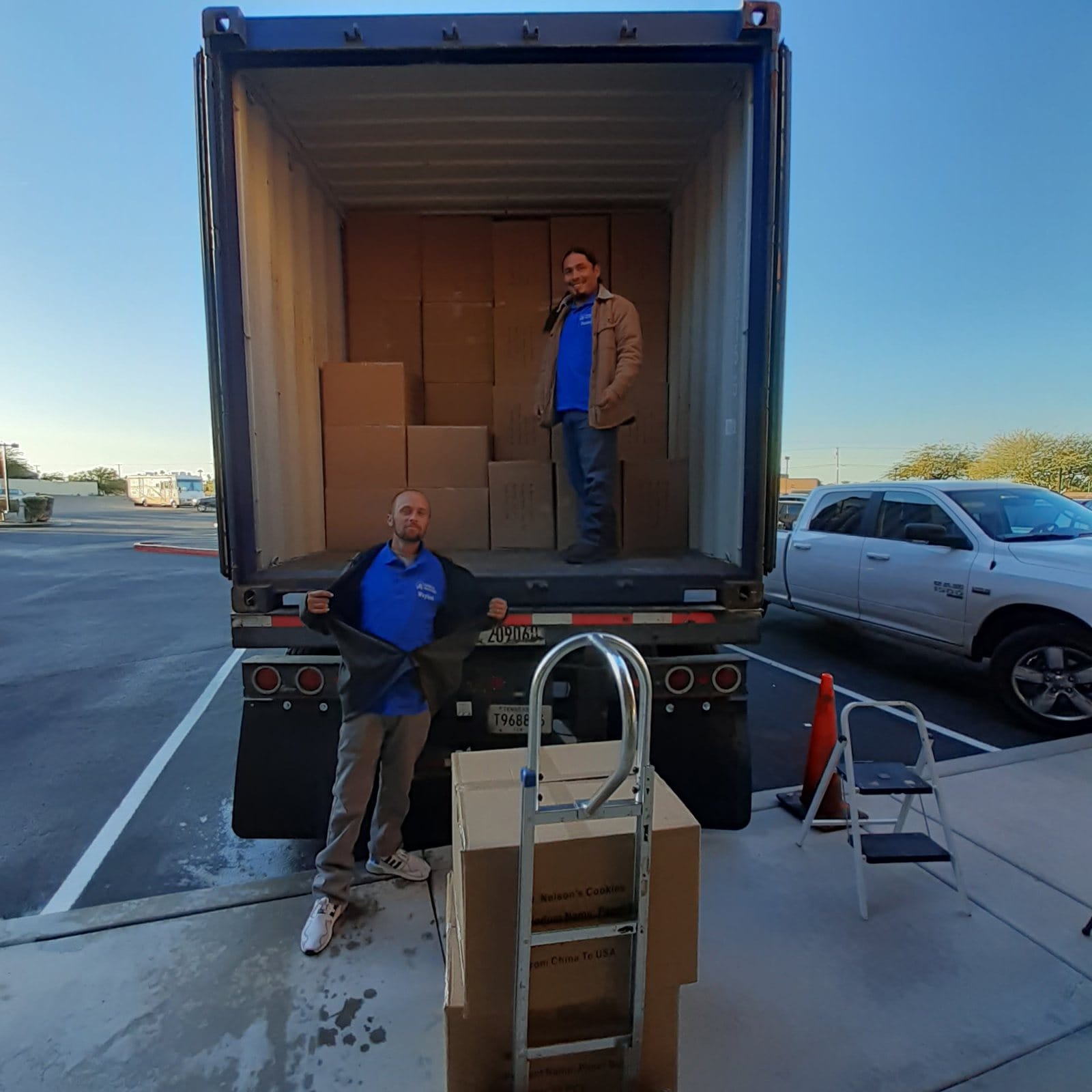 Two Garcia movers loading a container stacked with packed boxes
