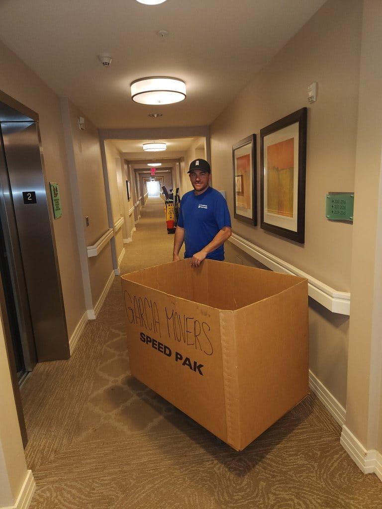 A Garcia mover guiding a moving box through a senior living community hallway