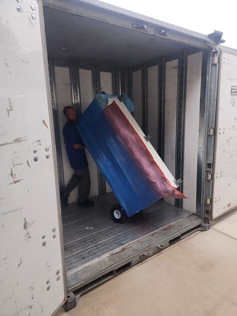 A Garcia mover rolling a wrapped mattress out of the moving container